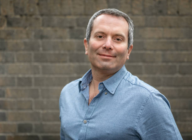 istock Middle aged man against a brick wall, looks at camera 1197825476