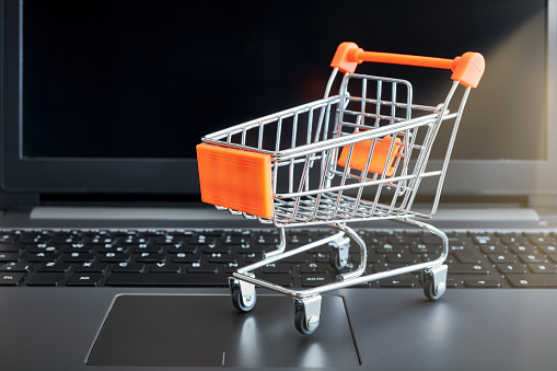 Online shopping concept with a shopping cart on a laptop computer background