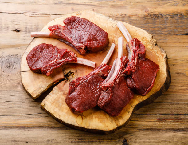 costillas de venado en rodajas crudas sobre fondo de madera - carne de caza fotografías e imágenes de stock