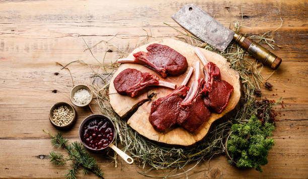 raw sliced venison ribs and meat cleaver on wooden background - venison imagens e fotografias de stock