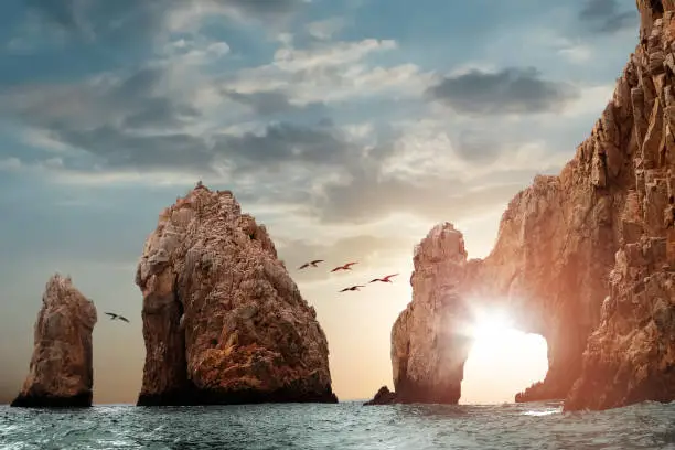 Photo of Rocky formations on a sunset background. Famous arches of Los Cabos. Mexico. Baja California Sur.