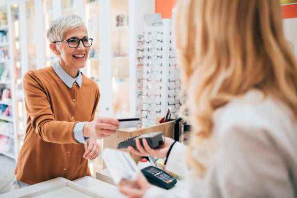Mature woman buying a medicine at the pharmacy Mature woman making a payment with credit card at the pharmacy. credit card purchase stock pictures, royalty-free photos & images