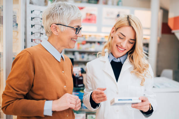 farmaceuta sprzedający lek dojrzałemu klientowi - pharmacist mature adult smiling senior adult zdjęcia i obrazy z banku zdjęć