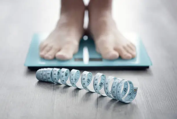 Photo of Feet on bathroom scale with tape measure