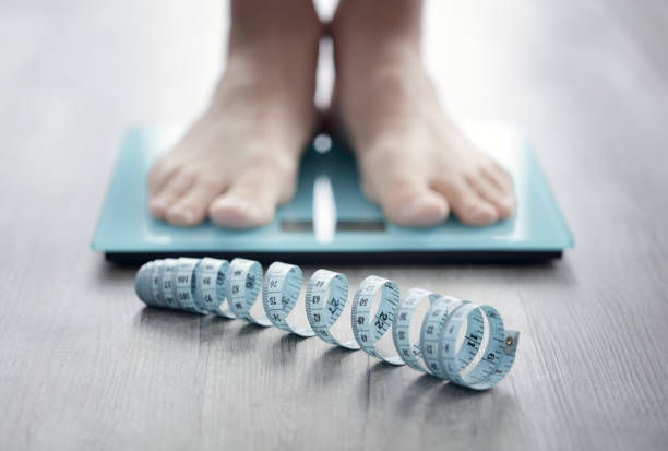 feet on bathroom scale with tape measure - weight scale dieting weight loss imagens e fotografias de stock