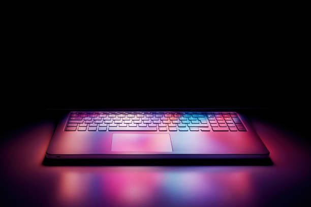 istock Half open laptop computer screen reflecting pastel colorful lights on the keyboard on black background 1197837690