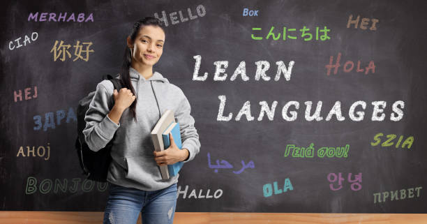 Female student standing in front of a blackboard with hello written in different languages