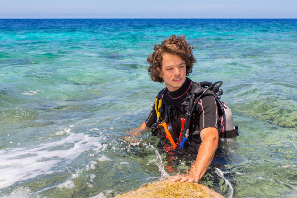 istock Young caucasian diver standing in blue sea 1197837719