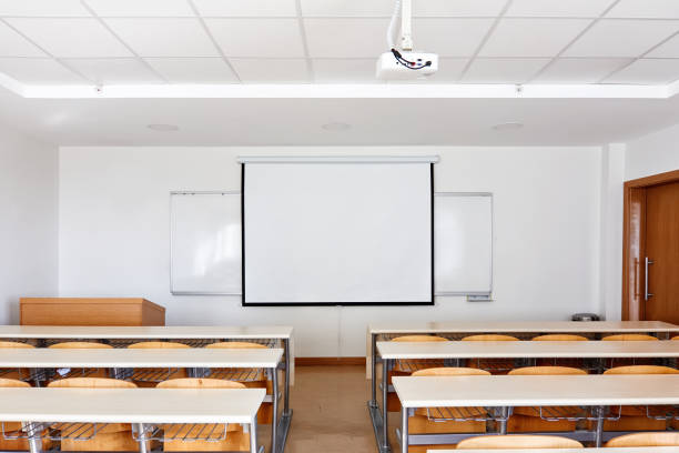 istock Classroom interior with projection screen, white board and wooden desks 1197838434