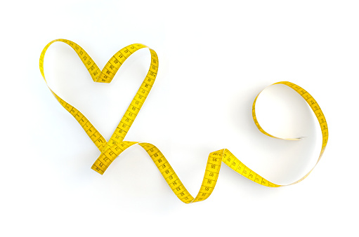 Corazón hecho de cinta de medición amarilla aislada sobre un fondo blanco. Concepto del Día de San Valentín. Concepto de estilo de vida saludable. photo