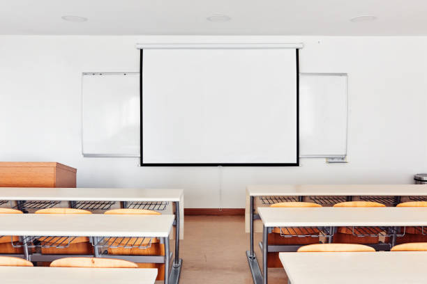Classroom interior with projection screen, white board and wooden desks Classroom interior with white board, projection screen and wooden desks projector screen classroom stock pictures, royalty-free photos & images