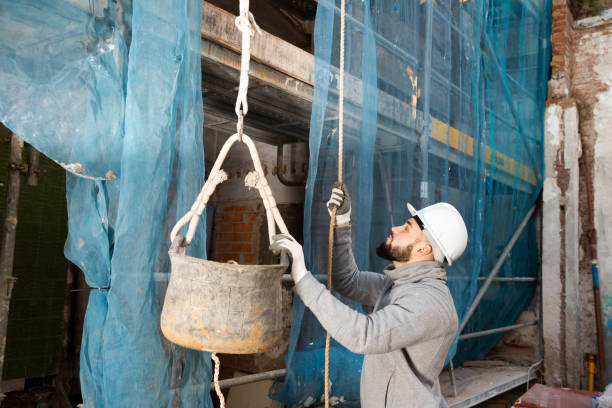 istock Man raising bucket with construction mortar on rope 1197843378