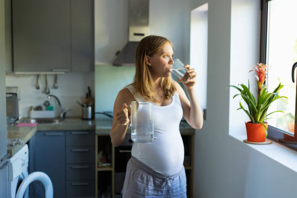 istock Pensive expectant mother standing in kitchen with jug 1197843530