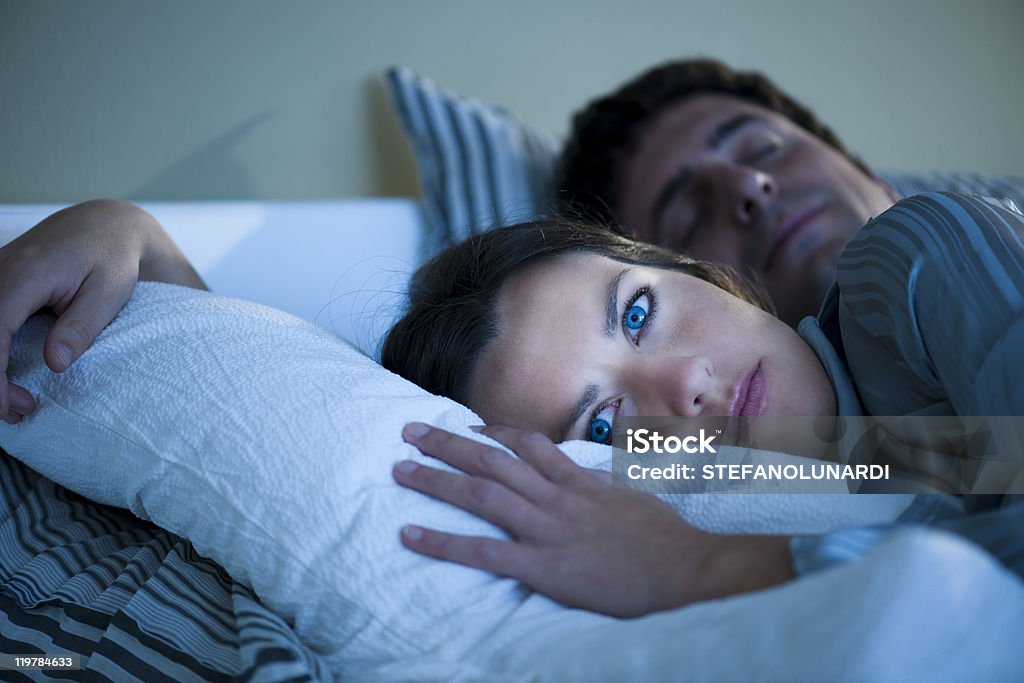 Young woman laying in bed with her eyes open  Insomnia Stock Photo