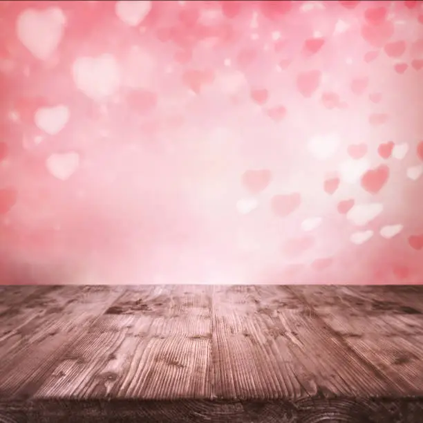 Flying pink hearts for valentines day. Abstract background and empty wooden table for a romantic love concept with space for design and text.