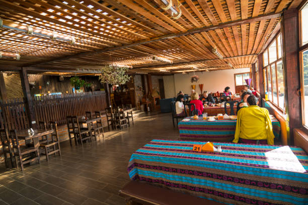 Tourists sitting around the dining tables, having breakfast in spa while on left side is restaurant's interior and on right side big windows with beautiful view. It is in small town Papallacta in Spa lodge, restaurant at altitude of 3,300 m in Ands, located in Napo Province near road from Quito to Amazon jungle, close to Volcano Cayambe, Ecuador.