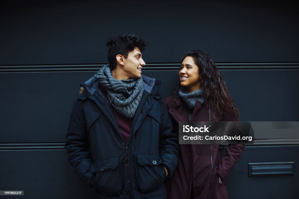 Portrait of a  happy young hispanic couple smiling while standing together  and looking at eachother outside Looking Stock Photo
