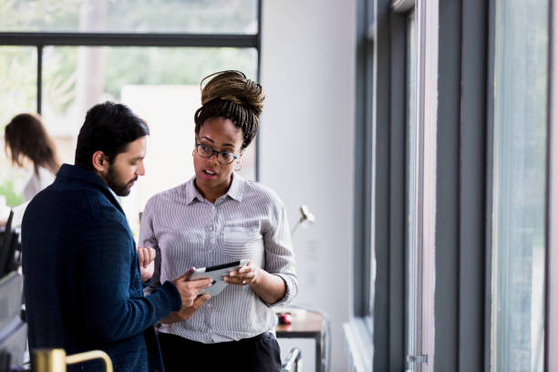 istock Mid adult colleagues stand and discuss information on tablet 1197855955
