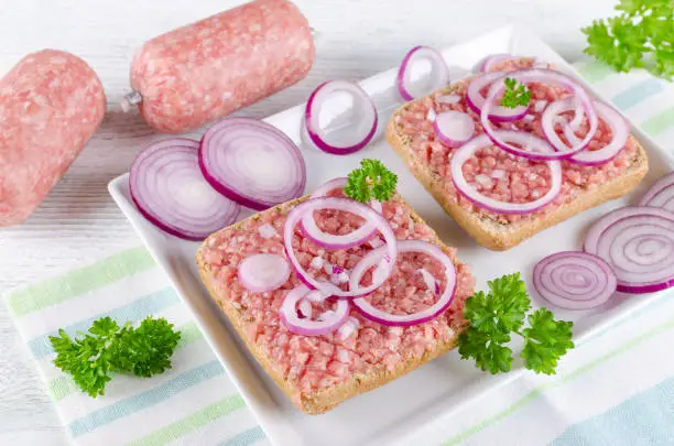 german food mett ground pork, raw meat with onion and parsley, selective focus