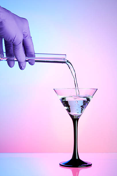 Pouring liquid from a test tube into cocktail glass stock photo