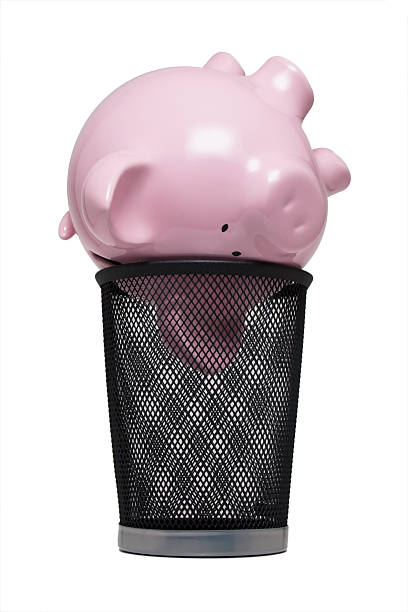 Piggy bank in a trash can stock photo