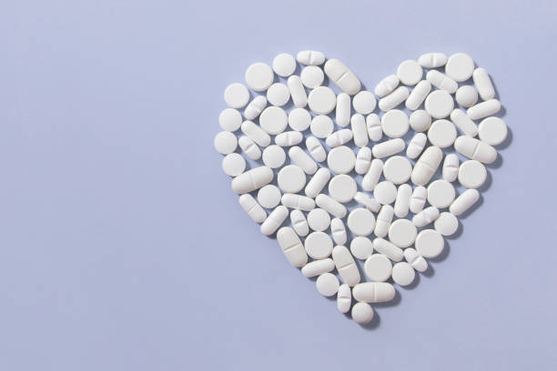 istock Heart Shaped White Pills on Blue Background 1197862865