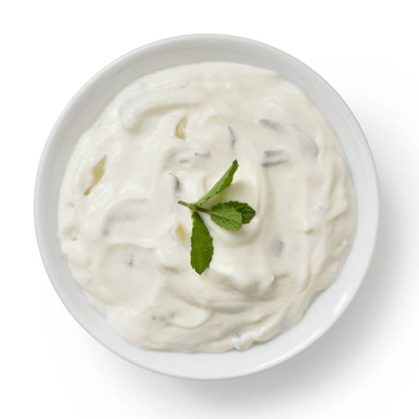 Tzatziki in white ceramic bowl isolated on white from above. Mint leaf garnish. Tzatziki in white ceramic bowl isolated on white from above. Mint leaf garnish. tzatziki stock pictures, royalty-free photos & images