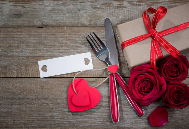 istock Valentines day background. Fork and knife on wooden table with gift package 1197868659