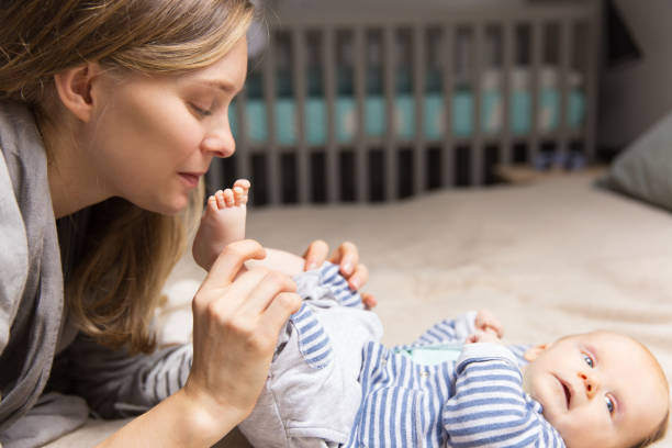 istock Cheerful positive new mom holding baby legs 1197868921
