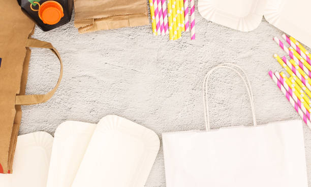 istock Eco friendly paper bag, bottles, straws, and plates on grey background 1197870384