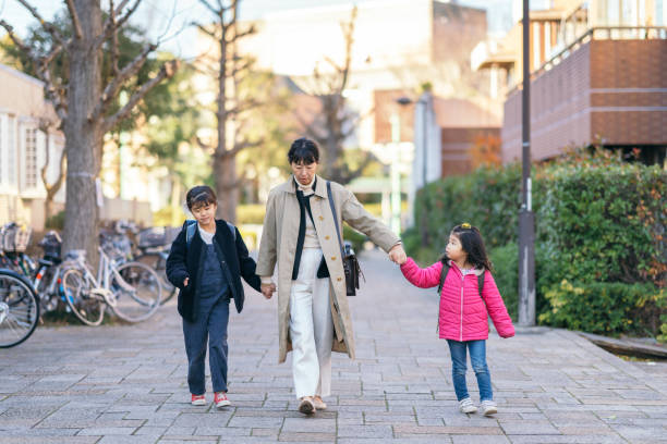 A working mother is walking in the street with her daughters. She is taking her daughters to school on her way to work.