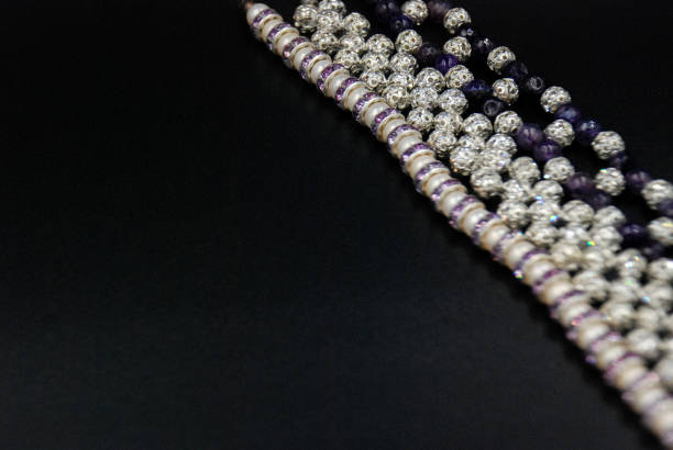 lignes de perles, de cristaux et de pierres violettes au coin du fond noir. concept d'art et d'artisanat. - paillette équipement dart et dartisanat photos et images de collection