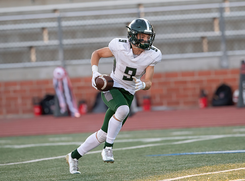 Athletic Football player catching and running with the ball during a game