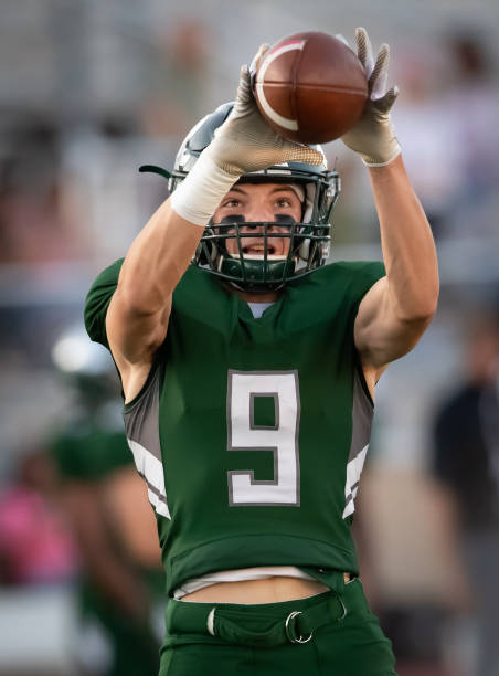 Young Football Player in Action During a Game Athletic Football player catching and running with the ball during a game offensive line stock pictures, royalty-free photos & images