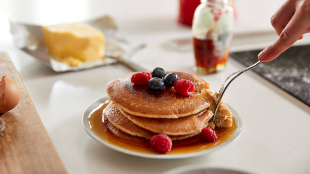 frau essen frisch gemacht pfannkuchen oder crepes mit sirup und beeren auf dem tisch für pfannkuchen tag - shrove tuesday stock-fotos und bilder