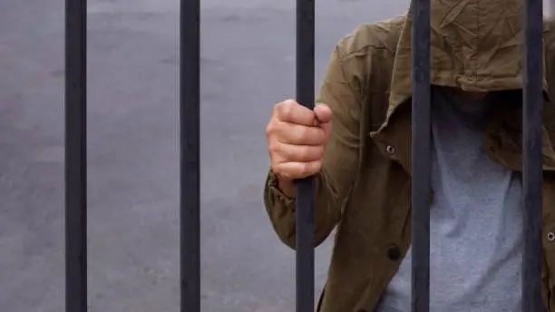 Photo of despair man holding iron bars