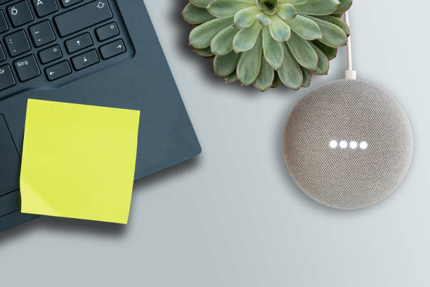 top view of Google Home Mini smart speaker while activated on table Hamburg, Germany January 06 2020: top view of Google Home Mini smart speaker while activated on table with laptop computer google home stock pictures, royalty-free photos & images