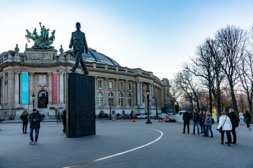 2019 The Grand Palais, the museum and cultural center on the Avenue de Champs-Elysees in the heart of Paris, France. It has an ornate glass roof and in the foreground is a statue of Charles de Gaulle.