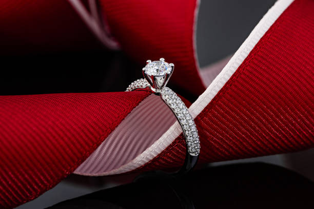 istock Wedding diamonds ring on black background with red ribbon 1197891076