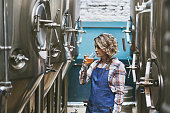 Hispanic Female Craft Brewer Examining Beer Sample