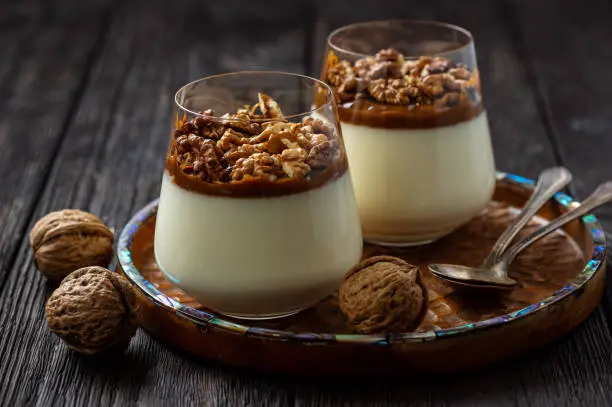 Italian dessert pannacotta in glasses with salted caramel and walnuts.