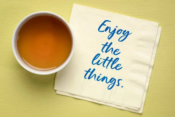 enjoy the little thing inspirational quote - handwriting on a napkin with a cup of tea, positive mindset and lifestyle concept