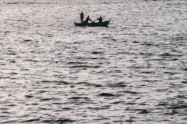 Three fishermen silhouetted in a rowboat in the Mediterranean port city of Alexandria, Egypt