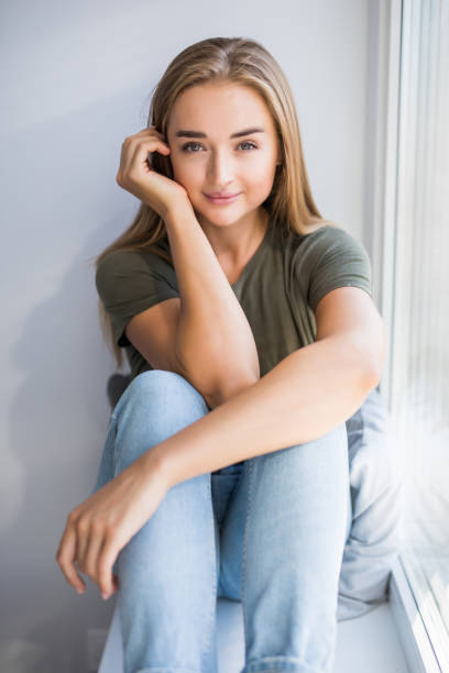 istock Sad depressed young woman having social problems sitting on windowsill 1197903113
