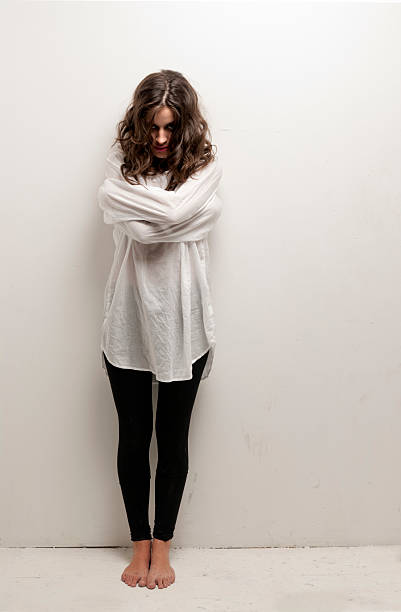 Young insane woman with straitjacket standing looking at camera stock photo