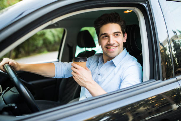 istock Transportation and vehicle concept. Young man drinking coffee while driving the car 1197913166