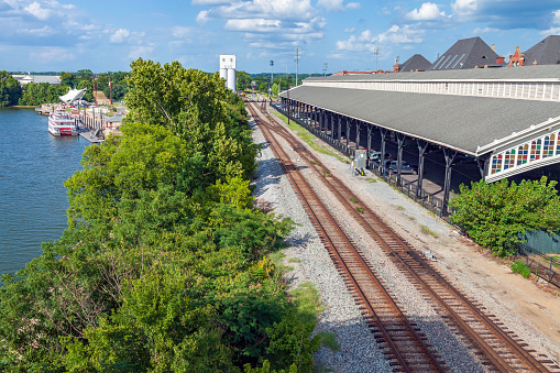 Union Station Tracks parallel a Lake, Paddlewheel Tourist Boat, and Band Shell on one side, and a covered parking garage servicing a Commercial District on the other side - in Montgomery Alabama