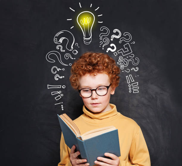 istock Child reading on blackboard background with lightbulb 1197913410