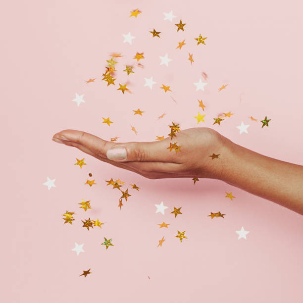 Gold confetti stars decoration in female hand on pastel pink background Gold confetti stars decoration in female hand on pastel pink background christmas nails stock pictures, royalty-free photos & images