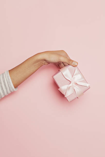 istock Gift in female hand on pink background. Abstract holiday present concept 1197914895